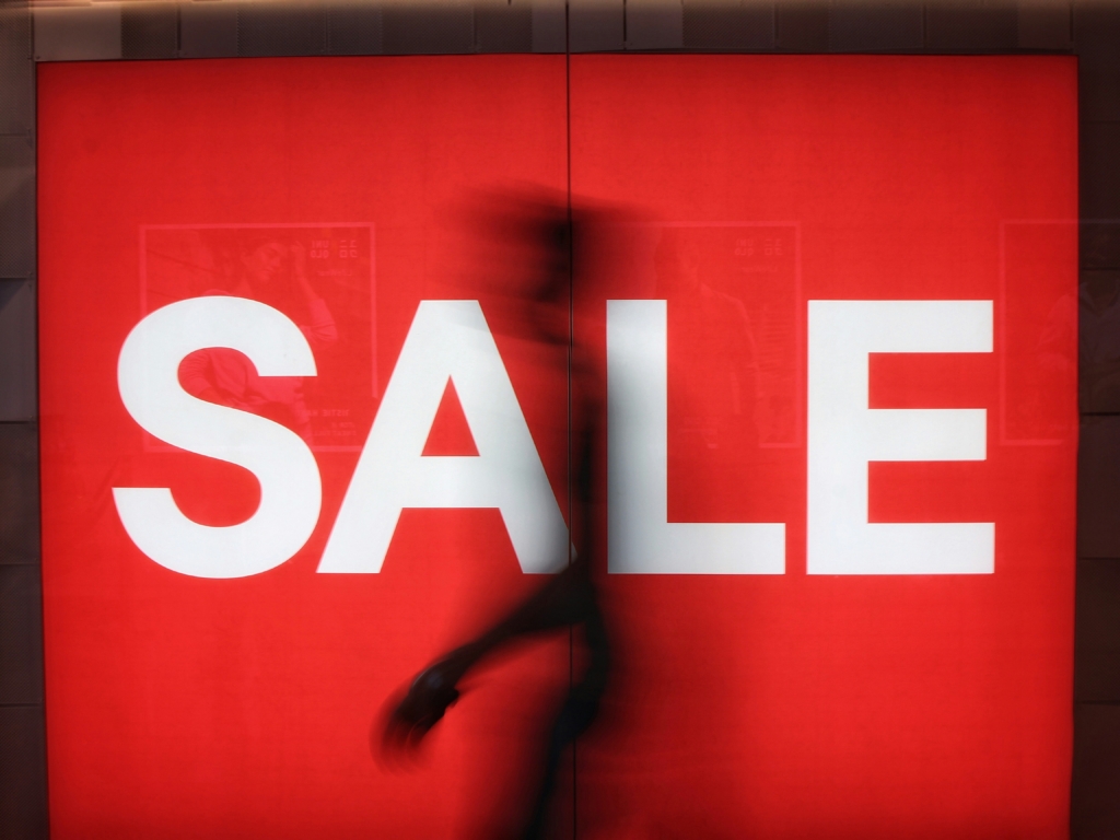 Bright red sale sign with a silhouette of a person walking by it.