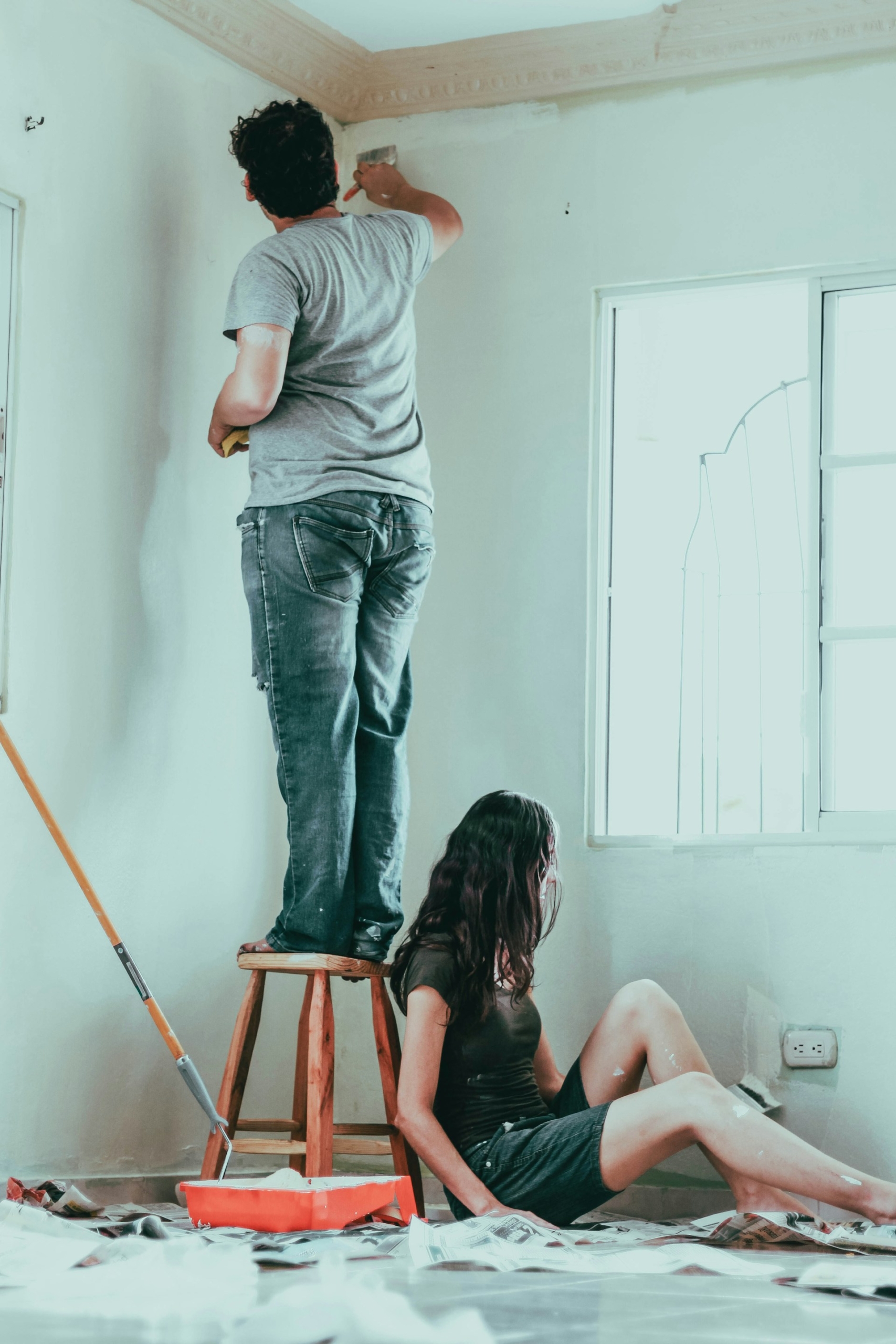 A couple paints a room that is being remodeled.