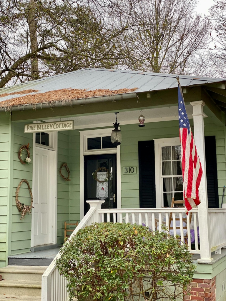 A small home with an American flag hanging on the porch.
