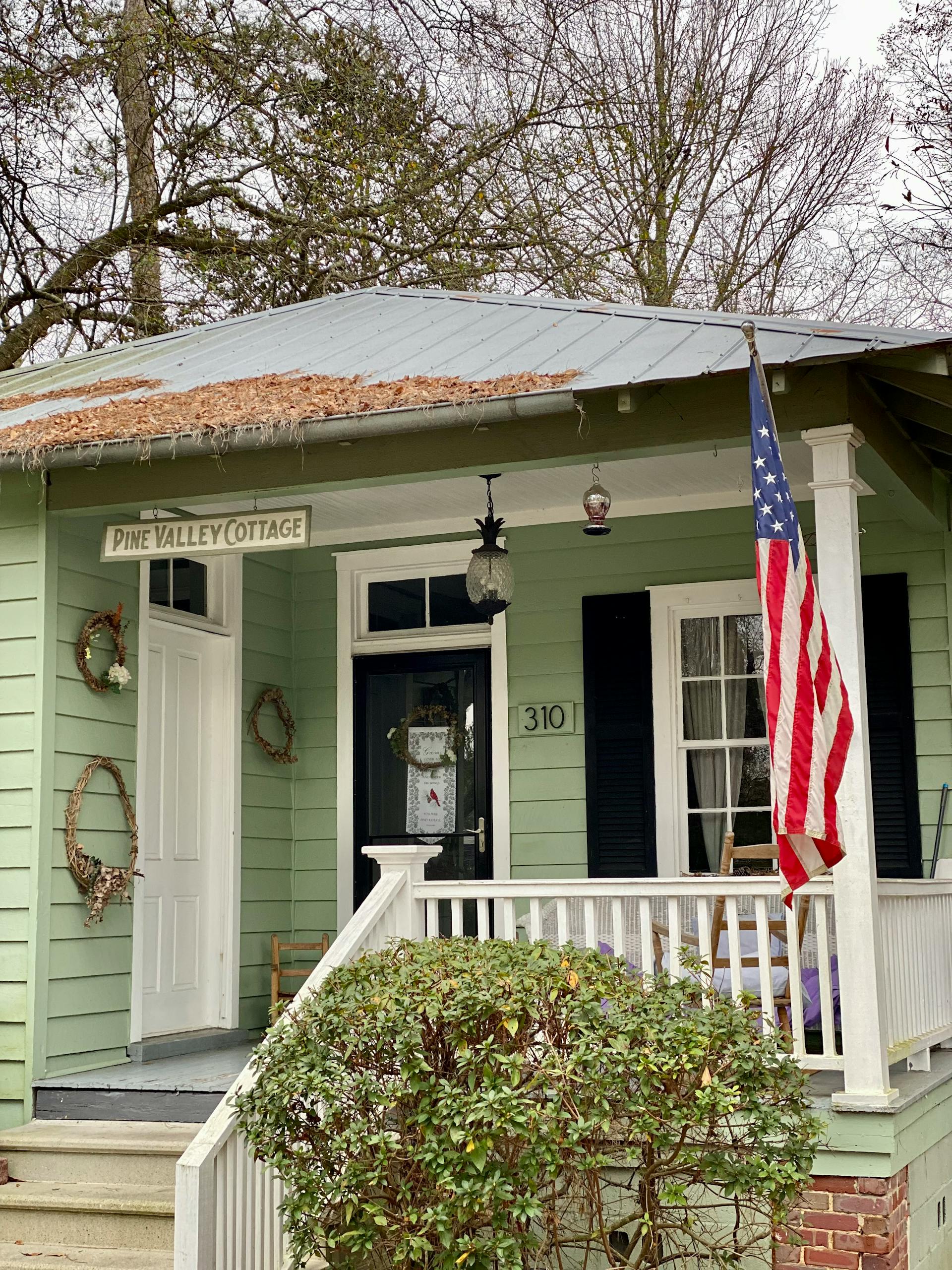 A small home with an American flag hanging on the porch.