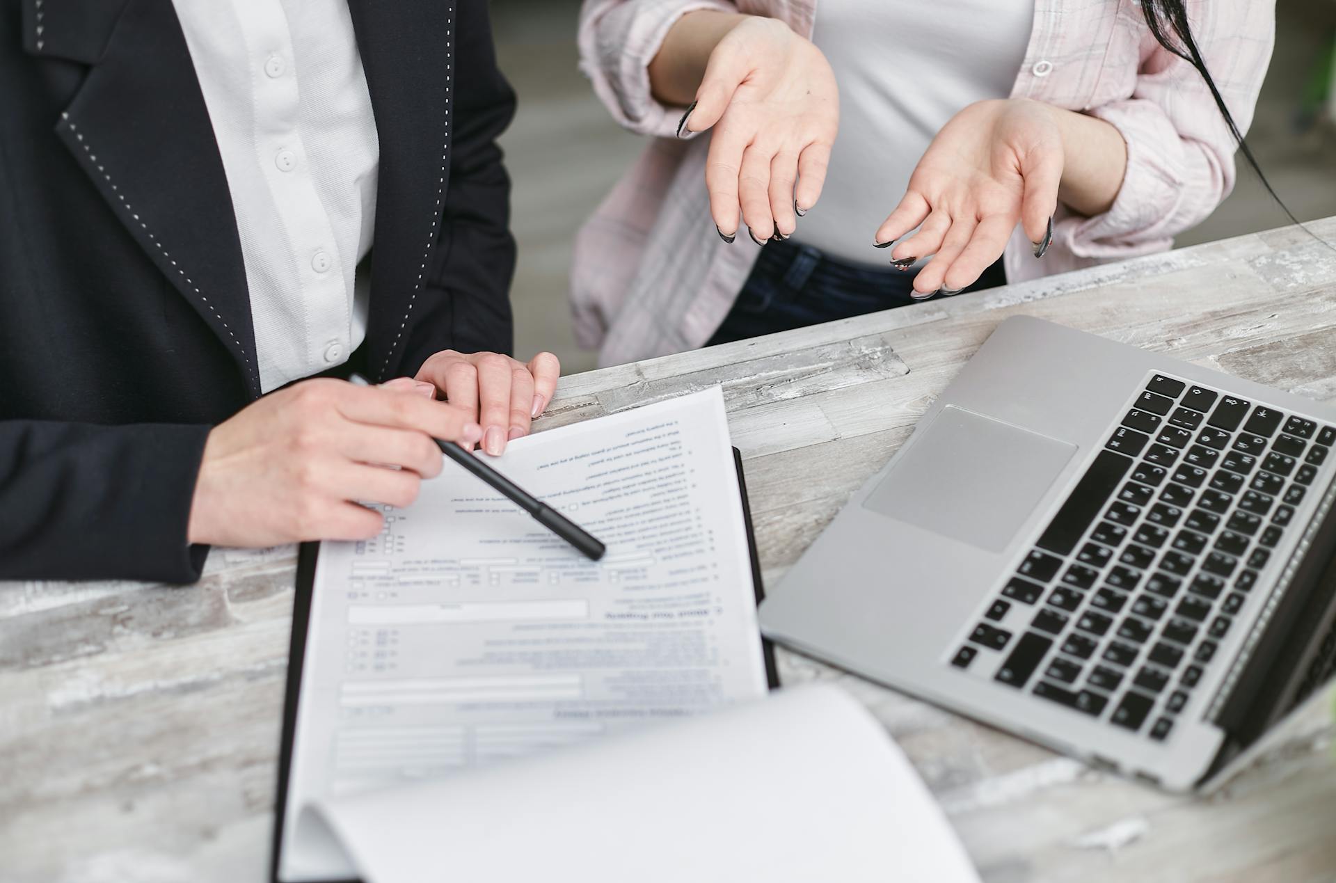 A person pointing to paperwork on a desk