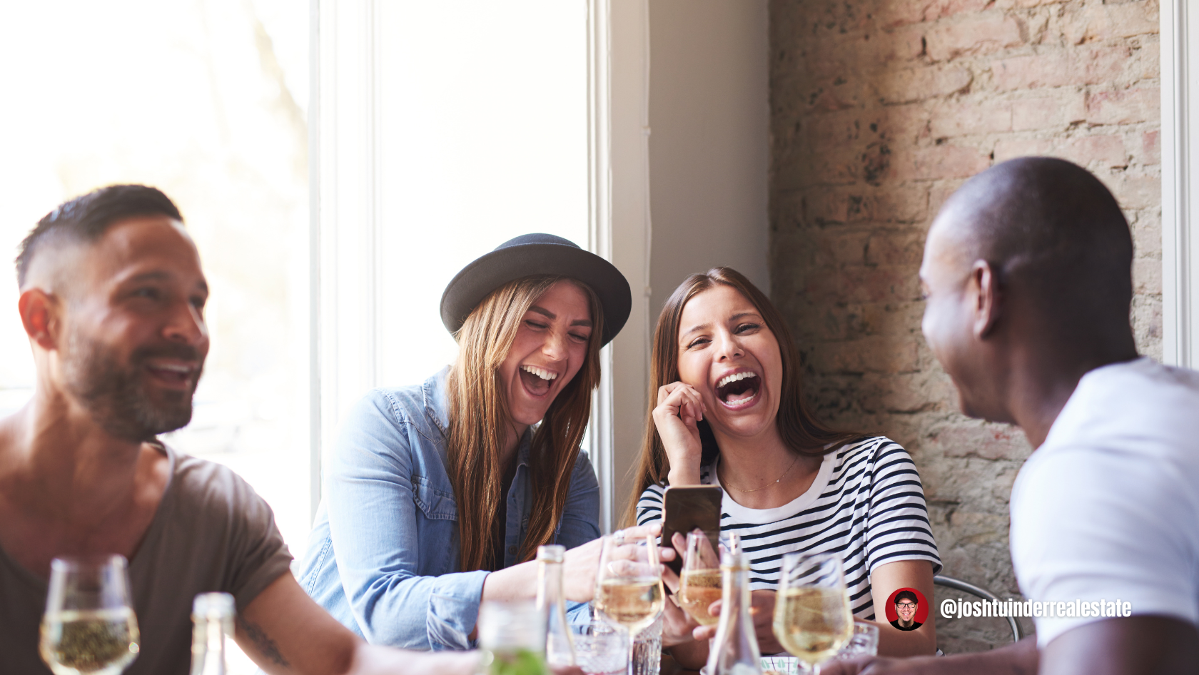 In a cozy restaurant setting, four friends enjoy each other’s company, smiling and laughing over drinks.
